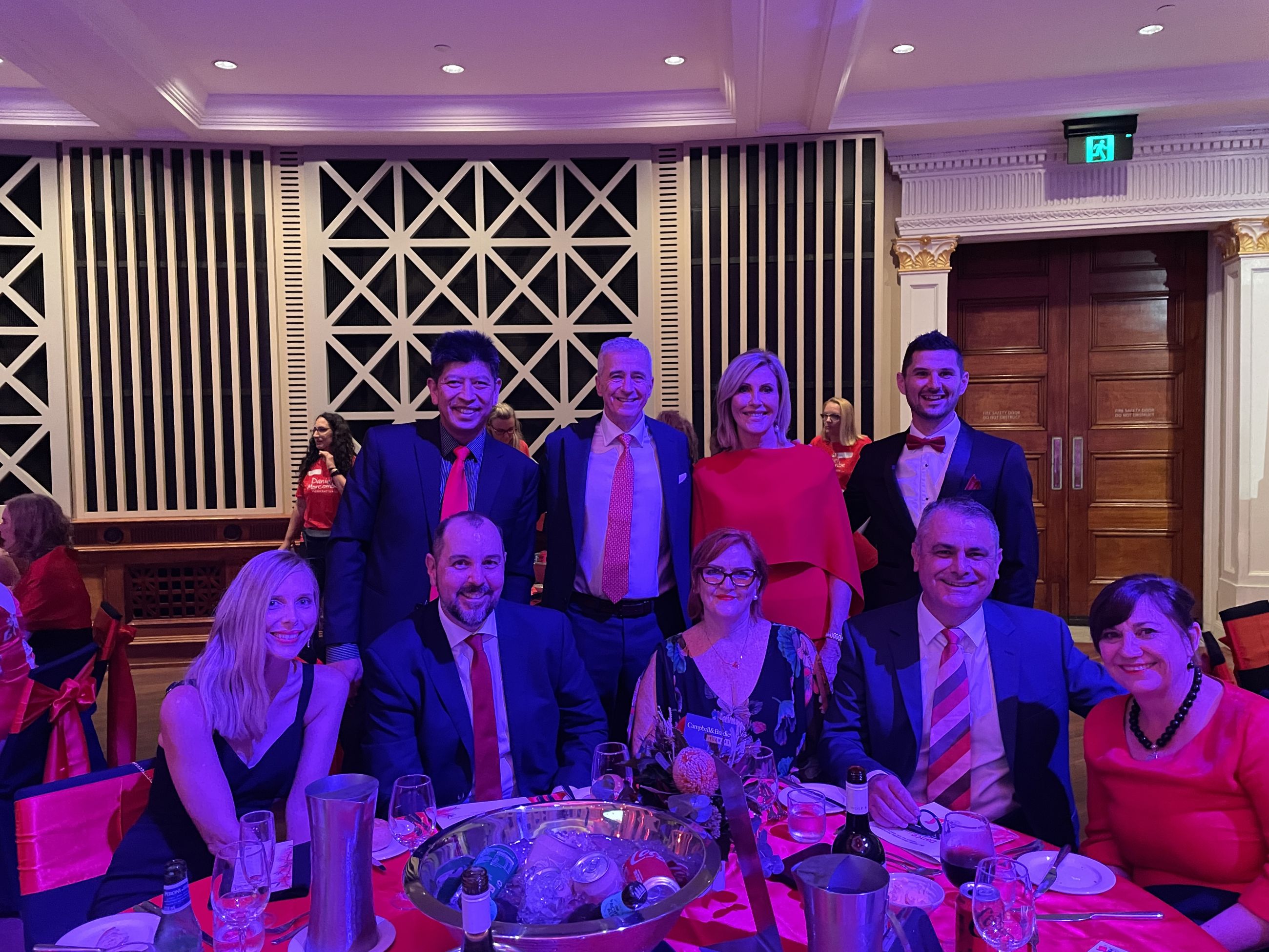 Reside Communities Ambassador, Kay McGrath standing with seven Reside Communities staff in Brisbane's City Hall for the “Dance for Daniel” fundraiser event.