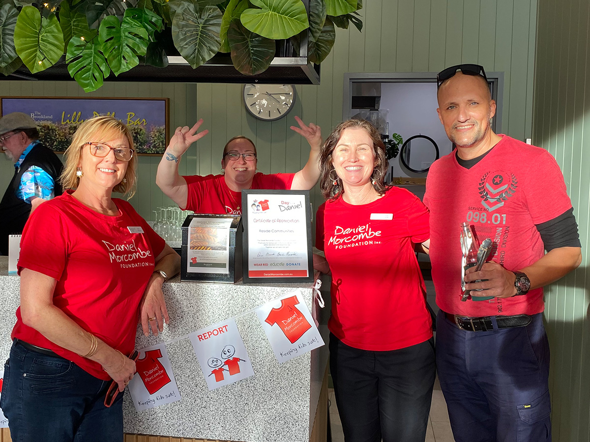 Brookland staff smiling in the café wearing red shirts for Daniel Morcombe fundraiser.