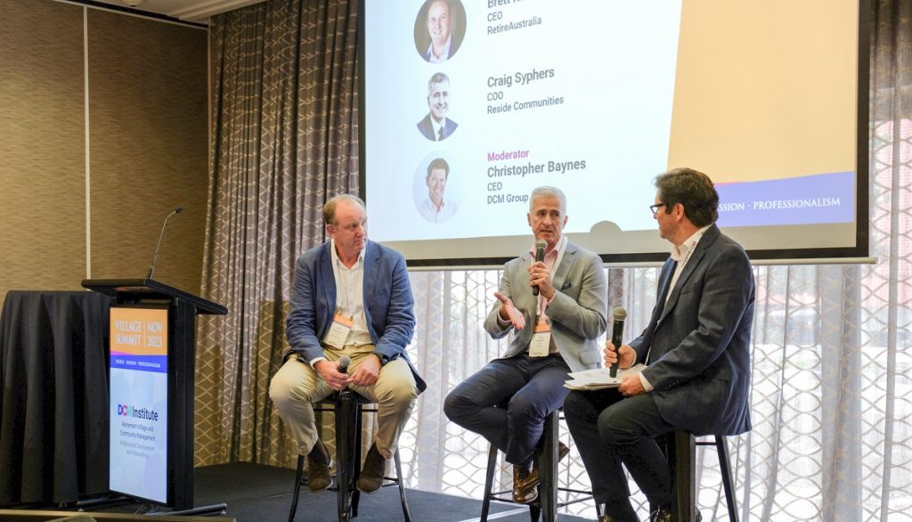 A panel discussion at the DCM Village Summit, with three men holding microphones and discussing the aged care sector. Men are Brett Robinson CEO of RetireAustralia, Craig Syphers COO Reside and Christopher Baynes CEO at DCM Group.