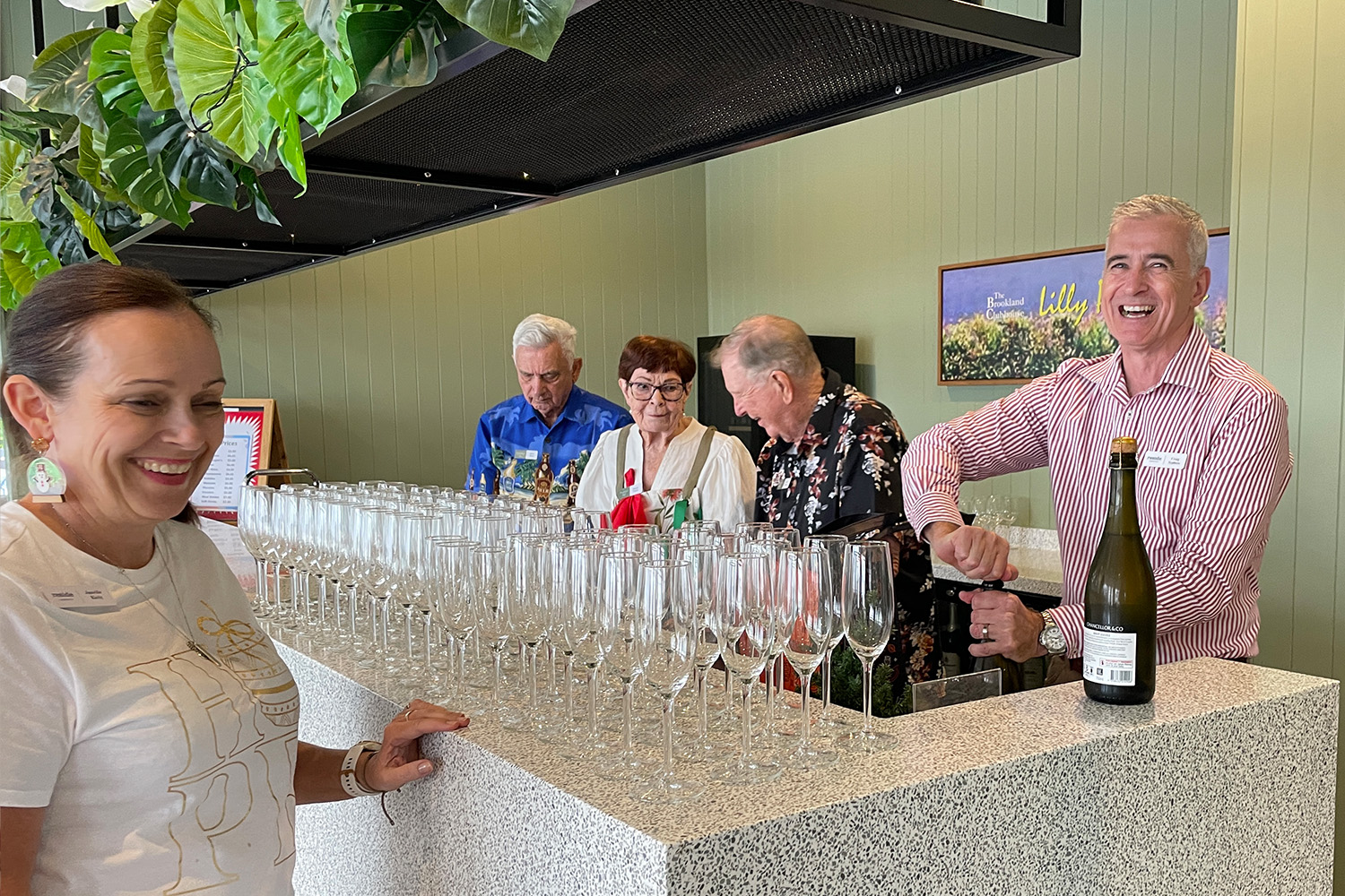 Chris Syphers pouring bubbly for residents in the Brookland Clubhouse for residents at Christmas party.